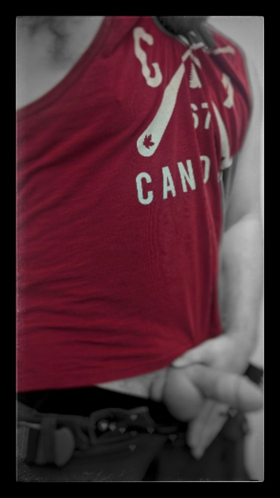 A vintage-esqe photo ofMe wearing a red Canadian tank top, enhanced. Just underneath the brim of my shirt, my half chub cock exposed.