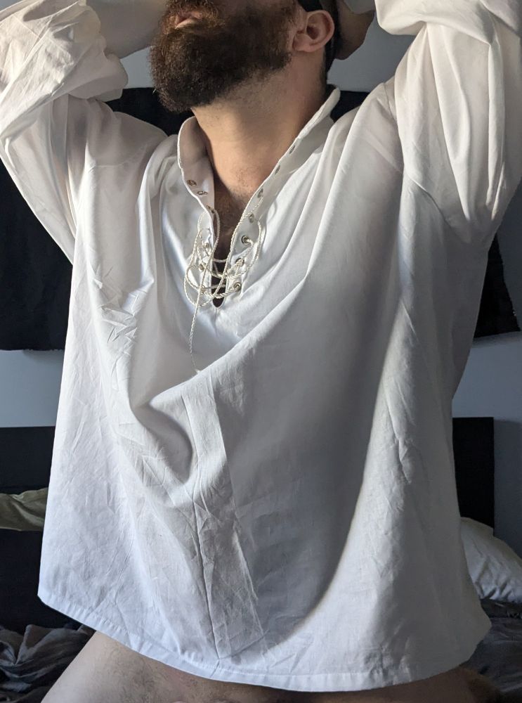 Picture of me on my bed in a poets shirt, cropped just enough to show I'm bottom less but hiding my erect cock.