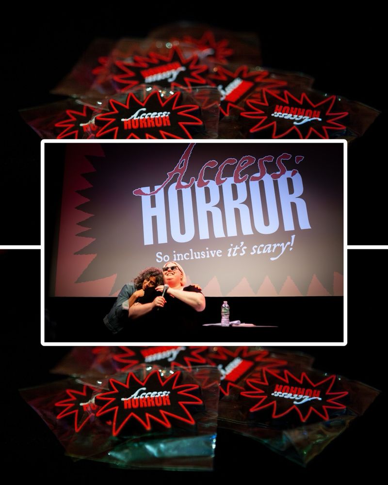A center image of Ariel Baska grinning in front of the Access:Horror logo as it’s projected on the film screen behind them. A woman with curly gray hair is hugging their shoulders from behind. The image is outlined in a white border that intersects with the above and below background images showing a pile of Access:Horror spiky logo magnets in red, black, and white.