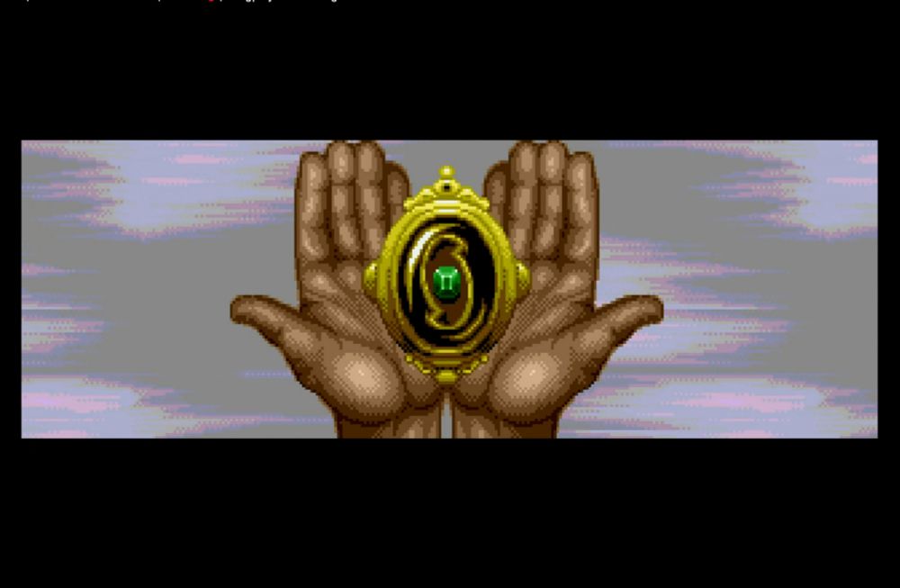 A screenshot of a cutscene from the Pirates of the Dark Water video game for Genesis and Mega Drive. It shows the hands of playable character Ioz, holding a gold amulet inlaid with a green emerald. This is one of the Treasures of Rule. Screenshot taken from the Kawaii Games channel on Youtube.