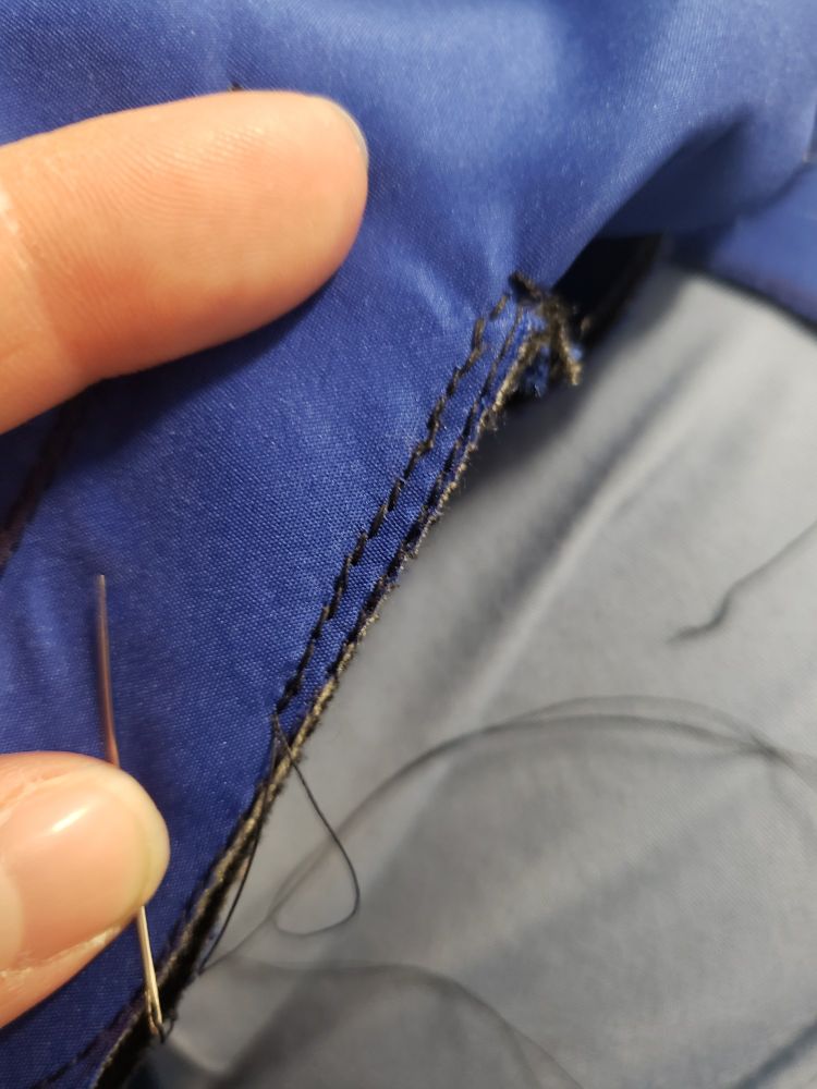 Close up of hand sewn back stitches on blue fabric