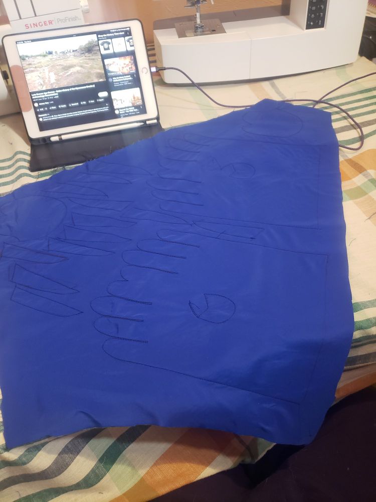 Blue fabric with the lines of a glove pattern stitched on the lines.