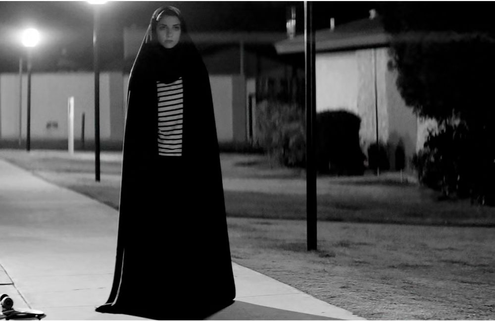 Scene from the mentioned movie - girl in a striped shirt and a veil on a black and white street lamp lit sidewalk
