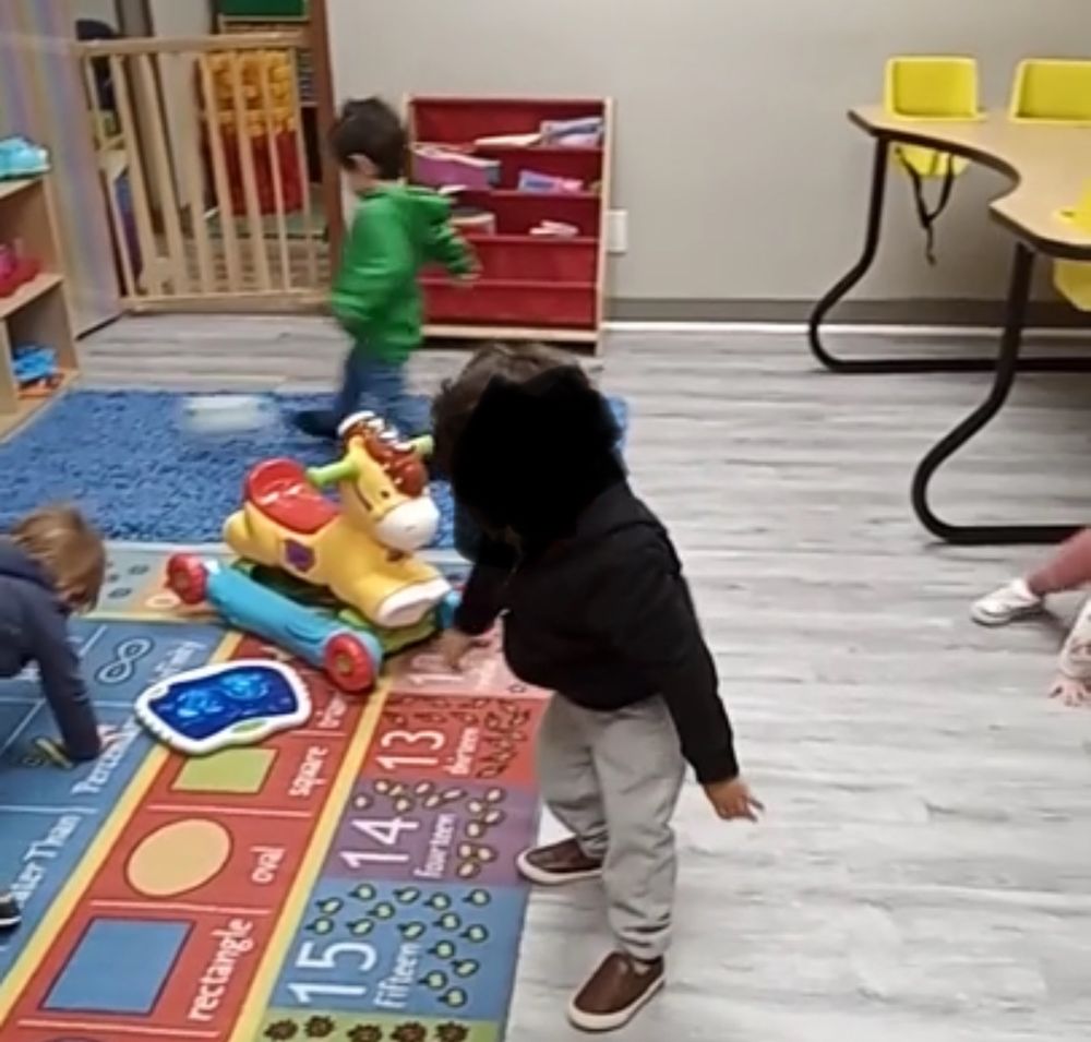 Kids at daycare playing while my son is in background with a soccer ball