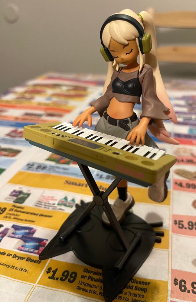 An image of one of Pop Mart’s Peach Riot Rise Up figures! The figure is Poppy - Electric Funk. The figure is of a girl with her eyes closed grooving while playing an electric keyboard.