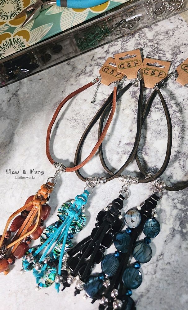 Photo of 4 color styles of the choker necklace with beaded leather tassels designed and made by Claw and Fang Leatherworks. The set includes camel brown, turquois, black and dark blue.