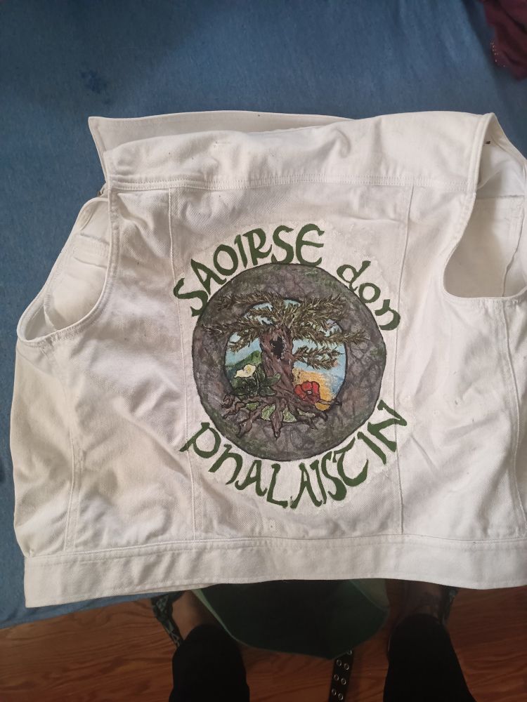 The back of the jacket. Hand painted on the back are the words Saoirse don Phalaistin: Freedom for Palestine in Irish. A tree in a stone circle in a roundel is featured as well.
