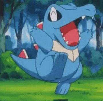 The Pokemon Totodile, a small, adorable blue-and-red creature resembling a baby alligator, dances joyously in a green forest, mouth agape in delight and little arms wiggling gleefully in the air.