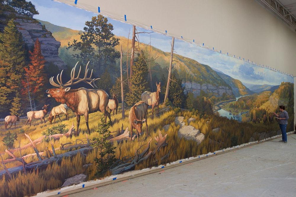 Beth Zaiken paints a monumental mural featuring elk, bison and mammoths in a scenic river valley landscape