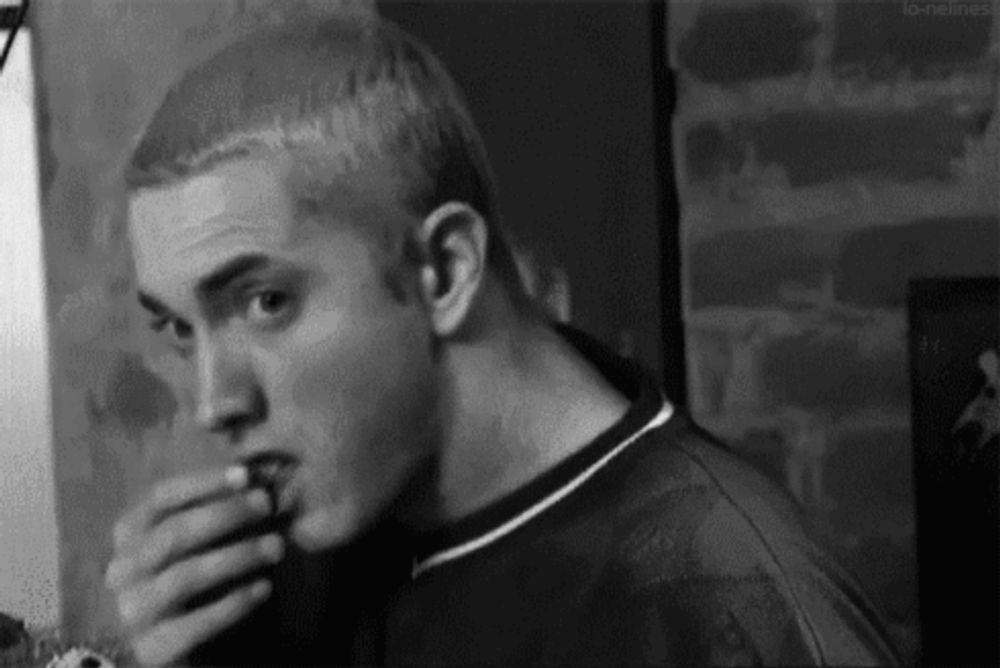 a black and white photo of a man eating a piece of pizza .