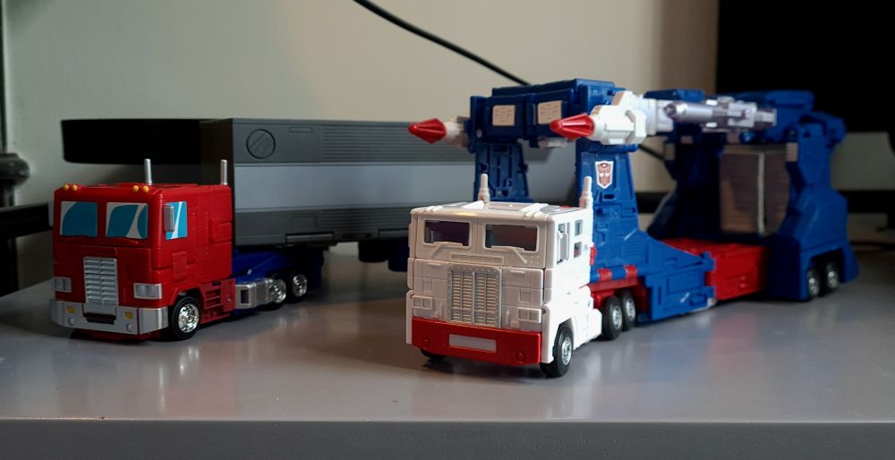 Photo graph of the new transformers figures Ultra Magnus (right a blue red and white car transporter truck) and Optimus Prime (left, a red and blue red truck with a grey trailer )