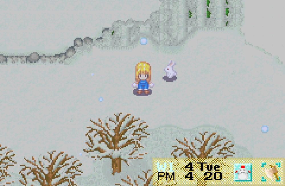Screenshot of harvest moon friends of mineral town showing the main character, a blond girl, standing in a snowy forest next to a snow bunny. Cute pixel art