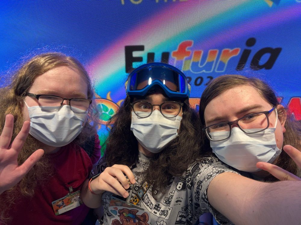Myself, Autumn, and Aubrey standing in front of a sign by the escalator about half an hour before the opening ceremonies.