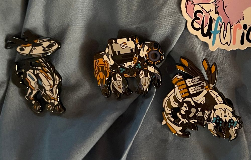 3 highly detailed, very high quality Horizon Zero Dawn themed pins bought from the Show and Tail booth. A Tallneck, Shellwalker, and Thunderjaw from left to right.