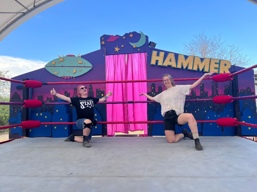 Me and Nikki posing in front of the talk show backdrop. It’s a cityscape with a ufo, stars, a moon, and HAMMER in lights