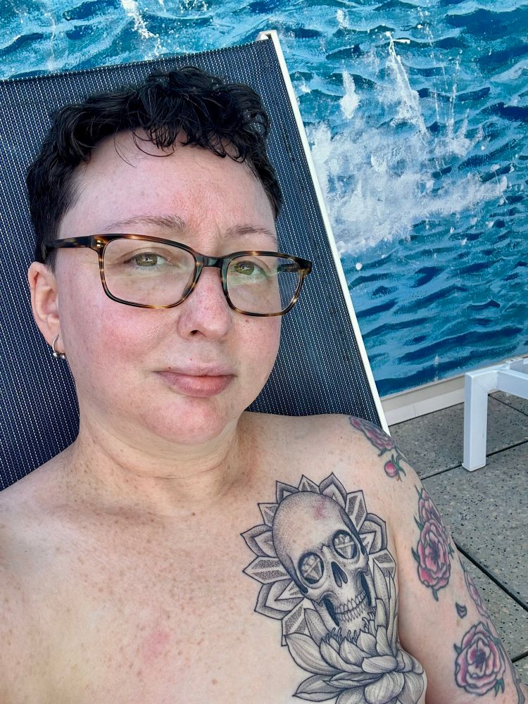 shirtless me sitting on a lounge chair by a pool
