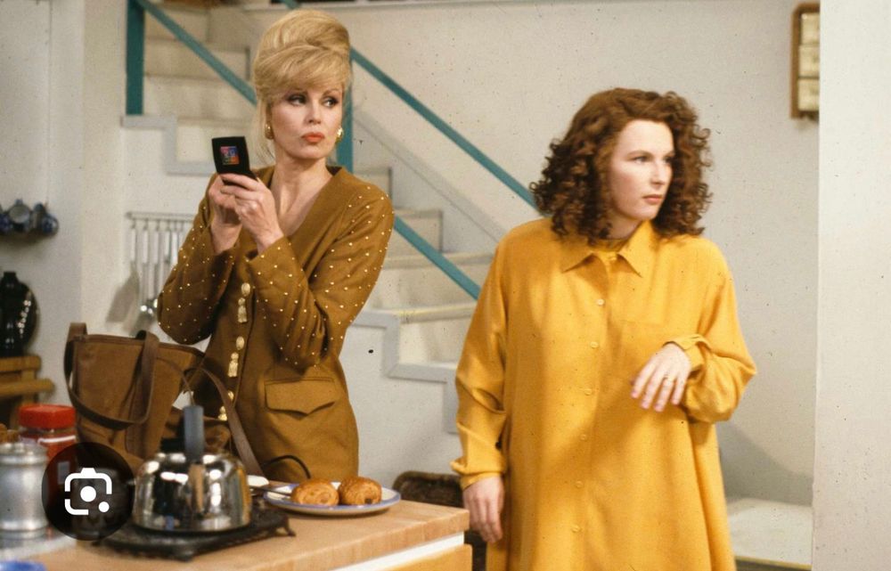Jennifer Saunders in an oversized mustard shirt dress and Joanna Lumley in an 80’s style suit jacket from an episode of AbFAb 