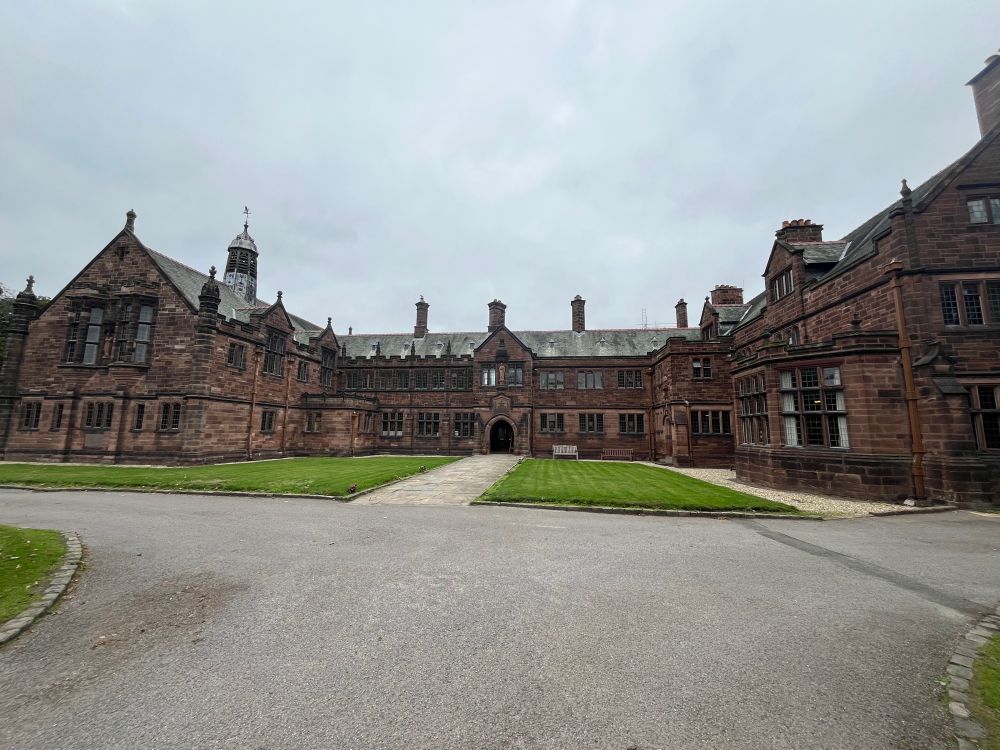 An Edwardian building of red stone with a central section and two wings on the left and right.