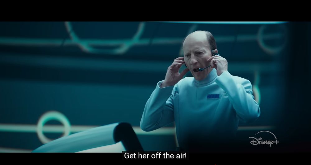 A scene from Andor. Supervisor Lagret (an imperial intelligence officer in a white uniform) shouts into headphones "Get her off the air!"