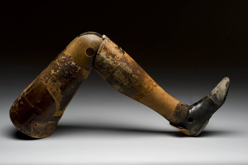 A prosthetic leg made of wood hinged at the knee. 