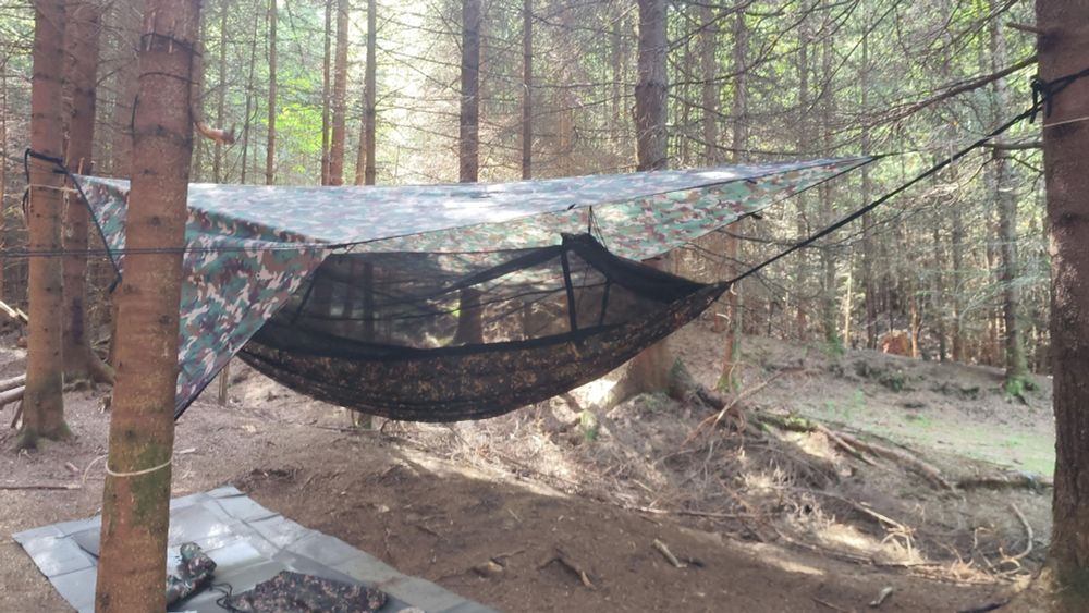 Hängematte mit Moskitonetz und Tarp darüber.