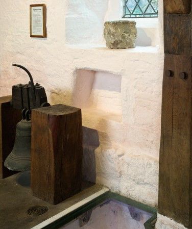 We are looking at a cast copper alloy bell sat between two blocks of wood. 