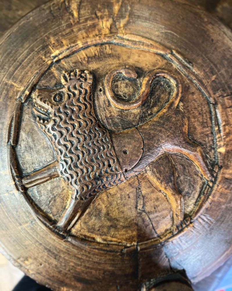 We are looking at a close up of a carved wooden lion on top of a tankard.