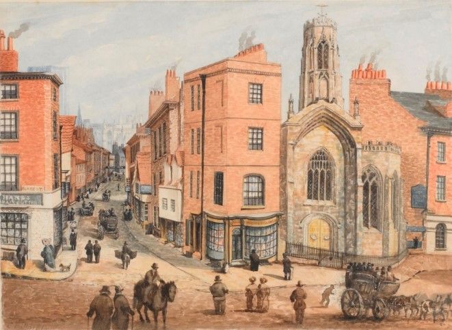 We are looking at a watercolour of a busy street scene showing an open square and a junction with a street leading off into the distance. On either side of the street are brick built buildings with shop fronts. On one side is a stone church with an unusual lantern tower. In the foreground is a packed stagecoach. 