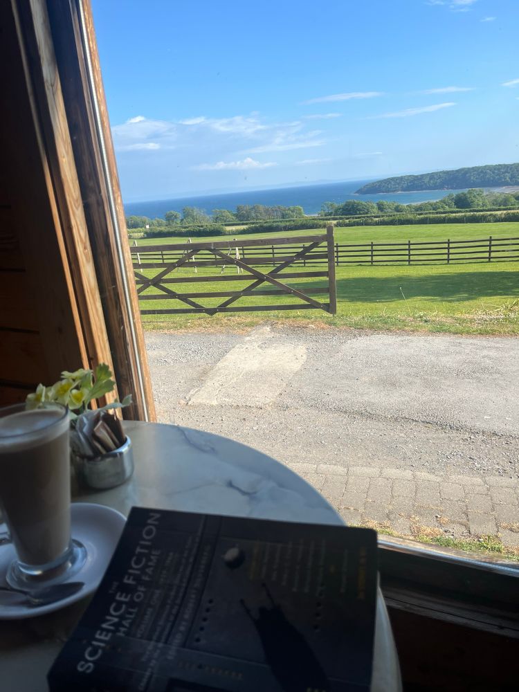 View of Oxwich Bay, Gower, Wales with coffee and a copy of the Science Fiction Hall of Fame in the foreground