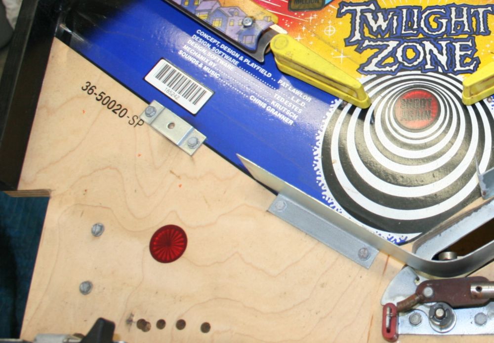 Section of a Bally Twilight Zone playfield with the metal apron removed. A single red lamp insert plastic is visible, but with no lamp under it.