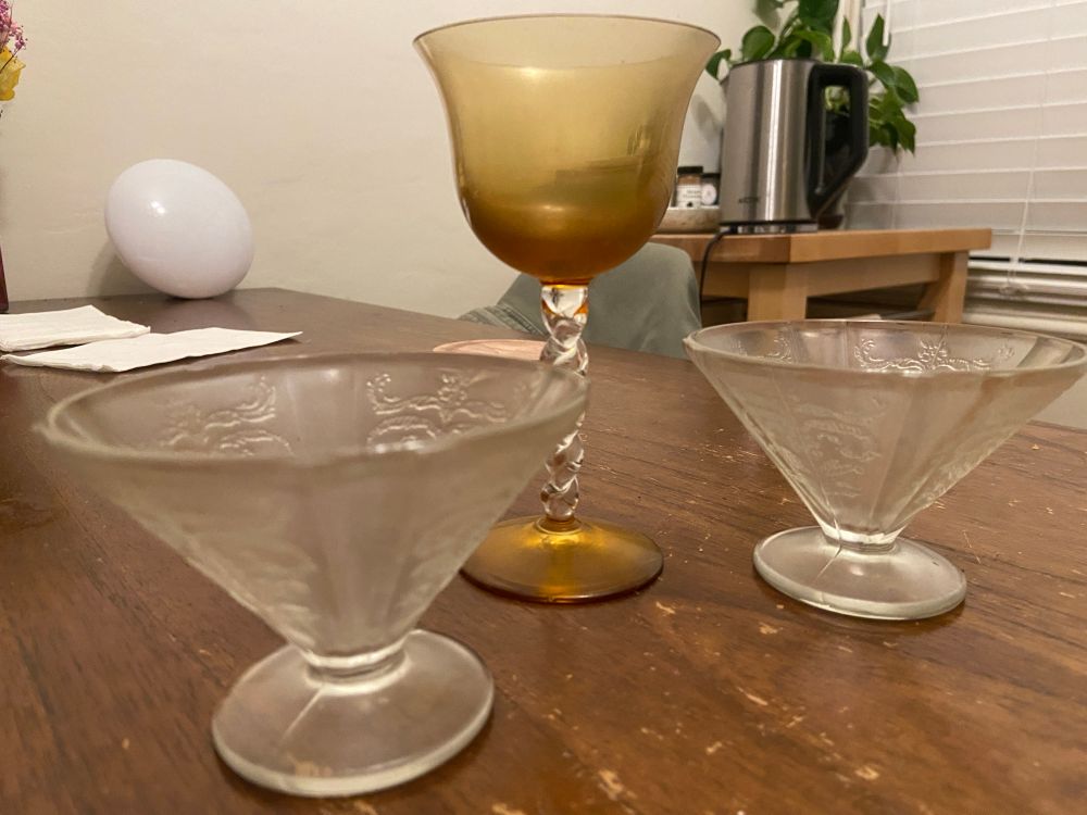 Three goblets, made of glass, two wide and stout with one tall and spindly. 