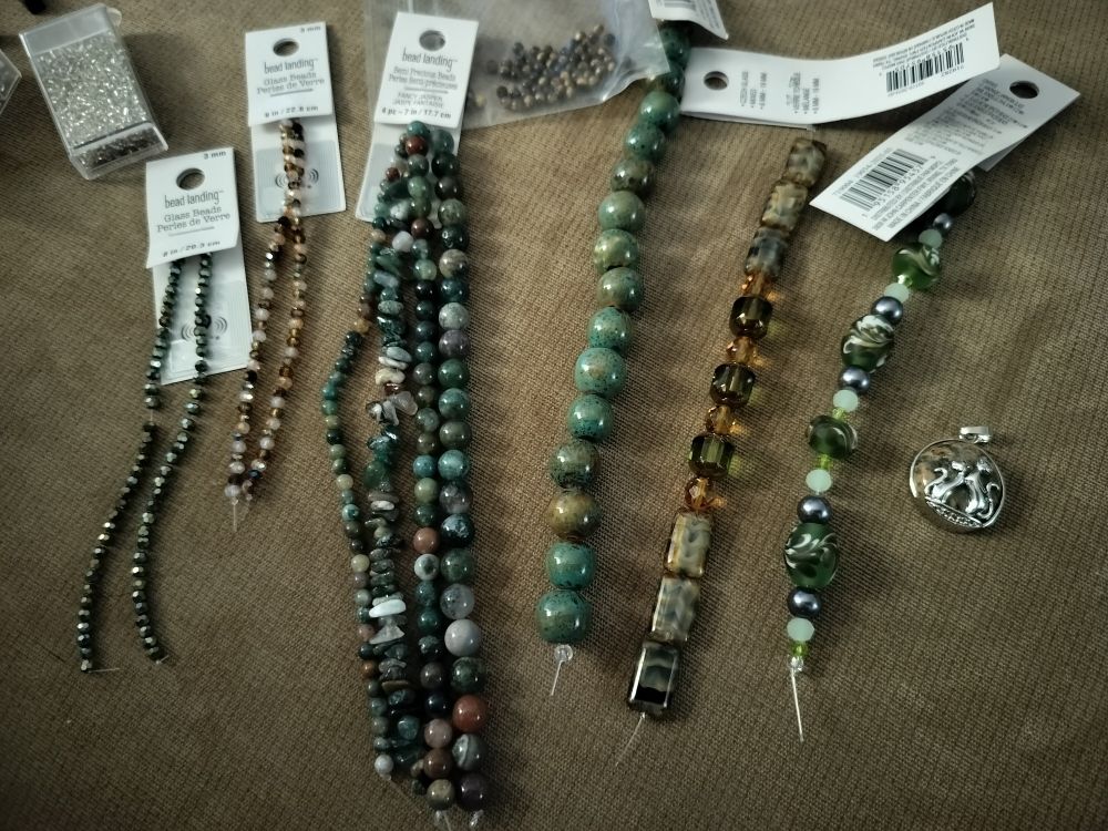 A whole bunch of green, brown, amber, and tan beads still strung and tagged. 