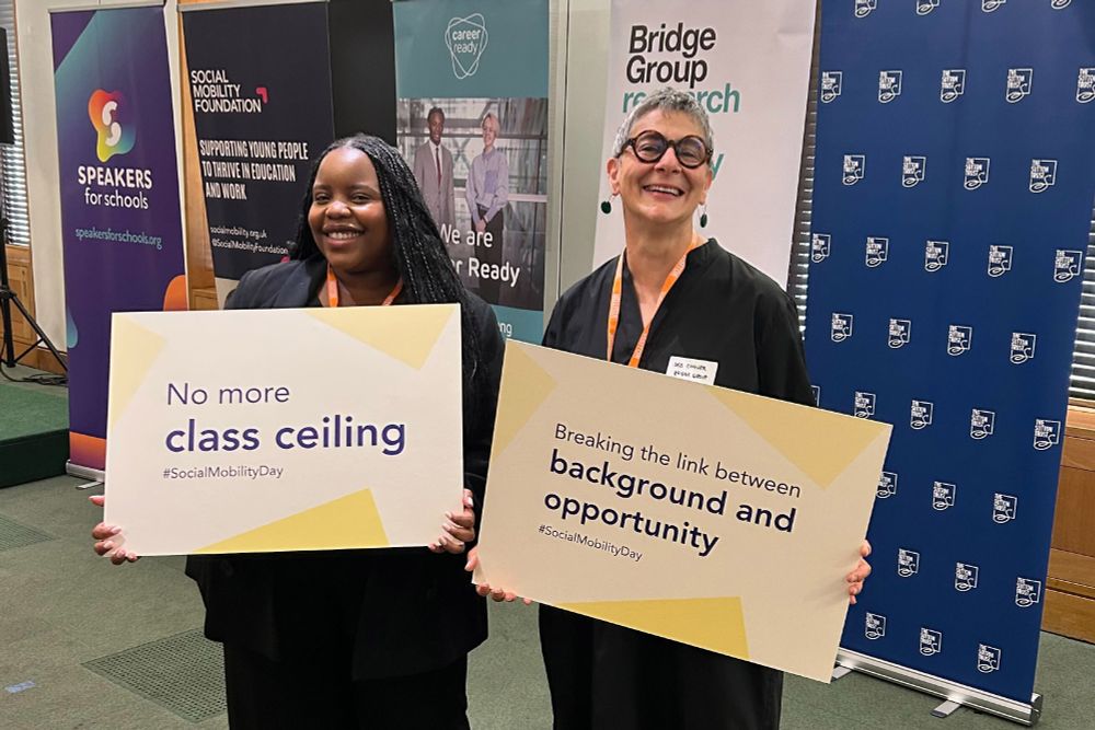 Patricia Ncube and Deb Connor from the Bridge Group hold placards at the launch of the Social Mobility Alliance.