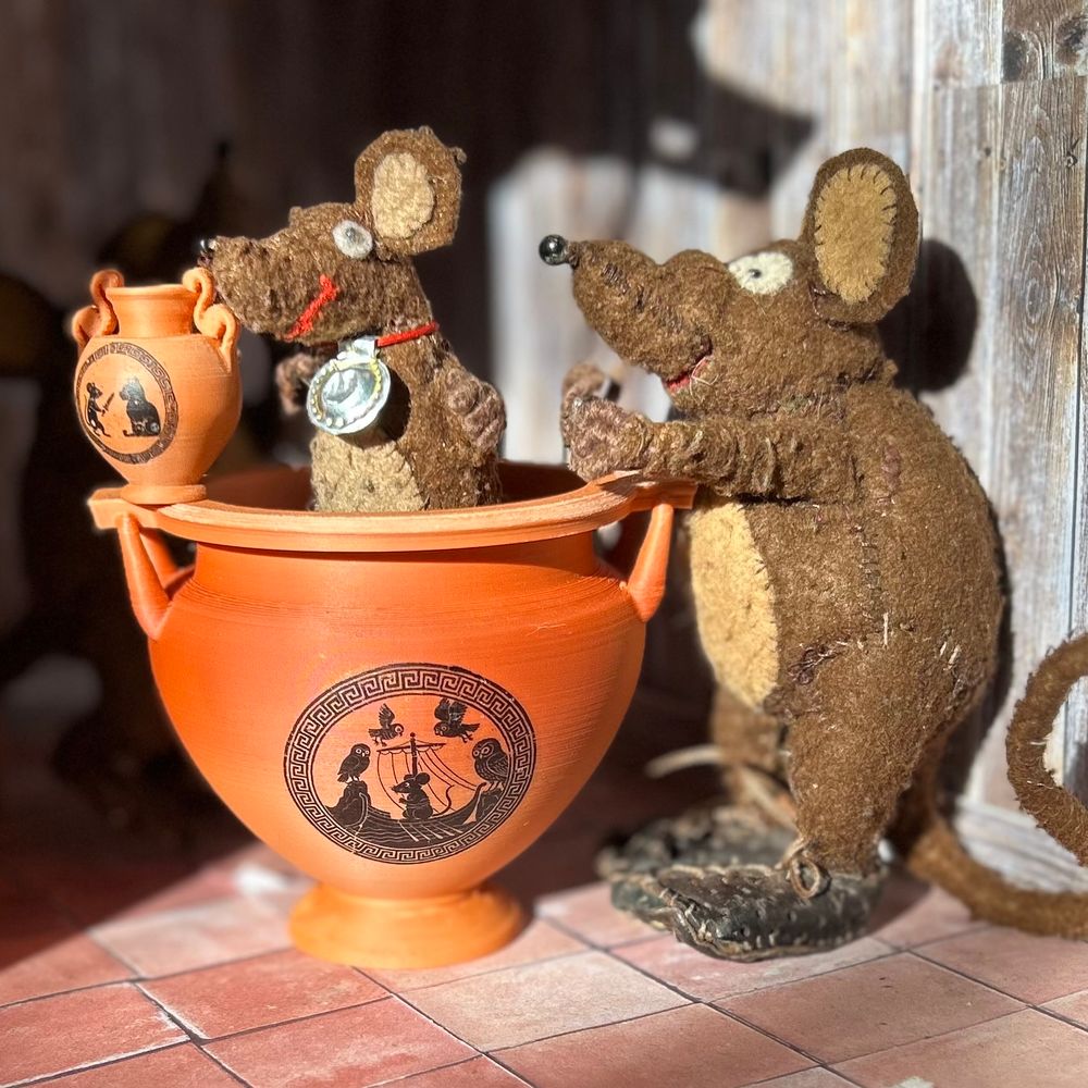 Photo of Minimus, Minima and Silvius, the Latin mice, with a set of 3D printed 'earthenware pottery' made specially for them by the mother of two of my students. Silvius is standing in a large vessel and holding a smaller one. Both pots have black-figure images based on Greek vase paintings. 