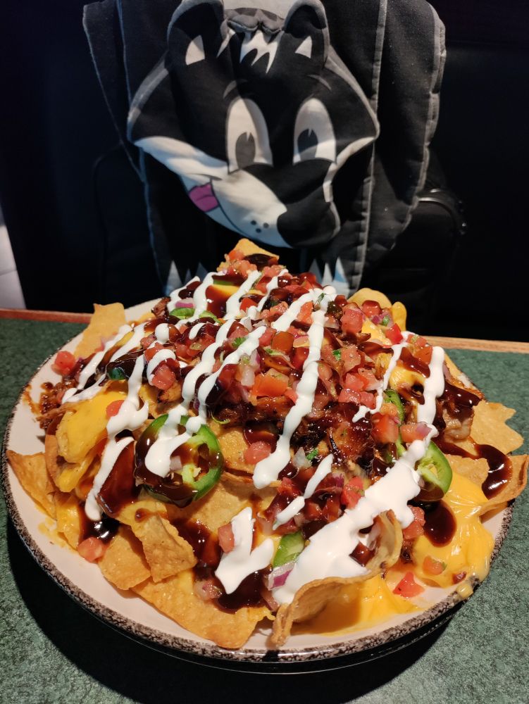 Heaping bowl of BBQ pork nachos. Skunk scarf in the background.