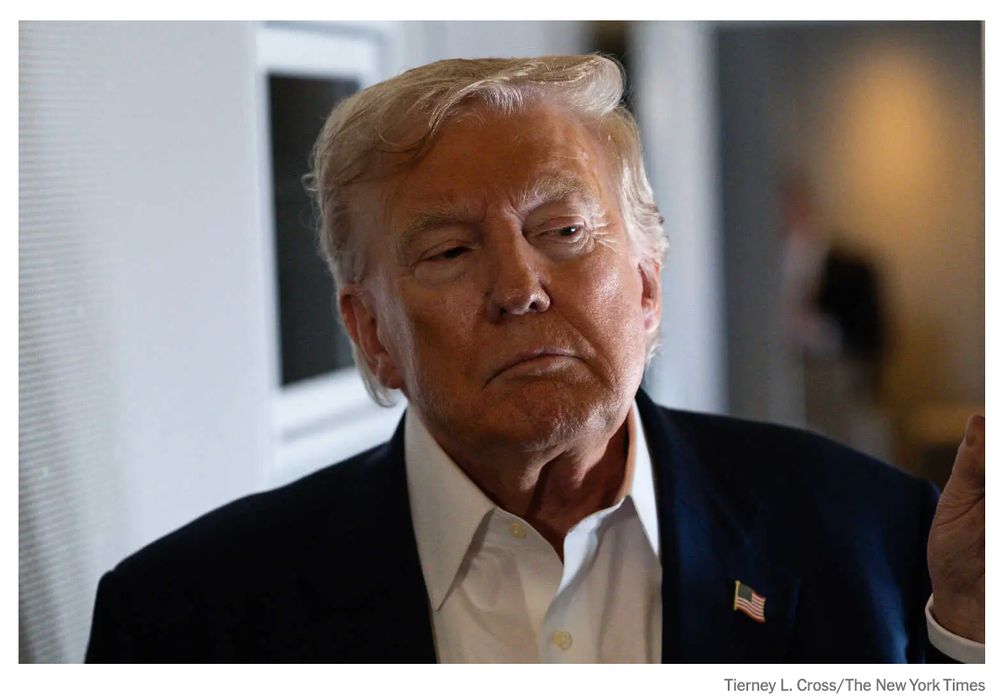A picture of Trump, in shadows. He has an open necked button-up on, with no tie.
