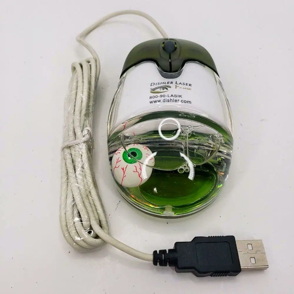 A computer mouse is laying on a white background. The mouse has a plastic toy green eyeball floating in green water inside of it.

