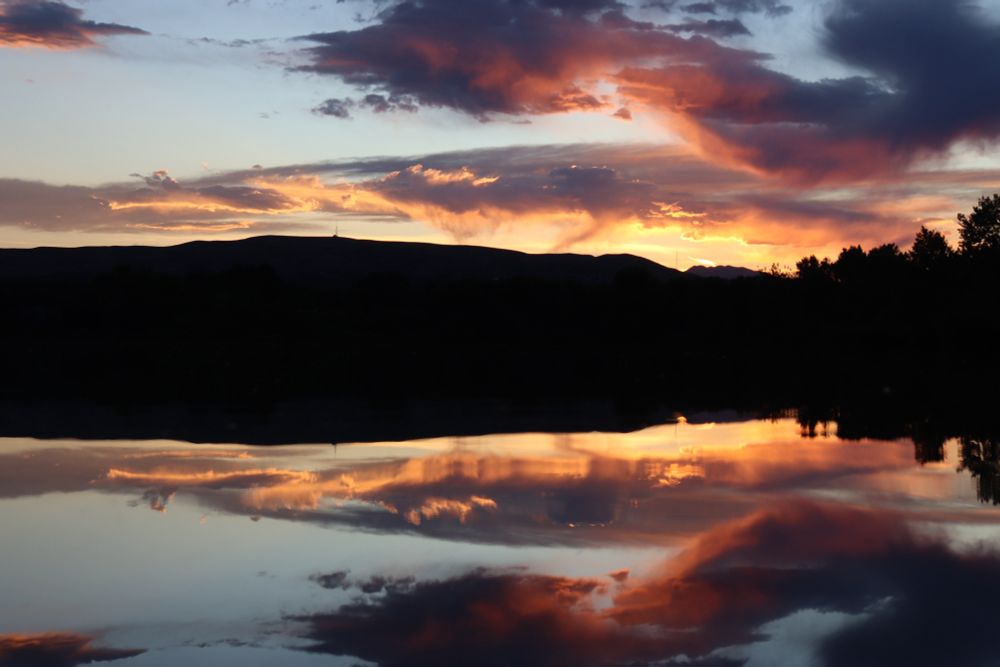 Red and golden clouds at sundown, reflected in calm water