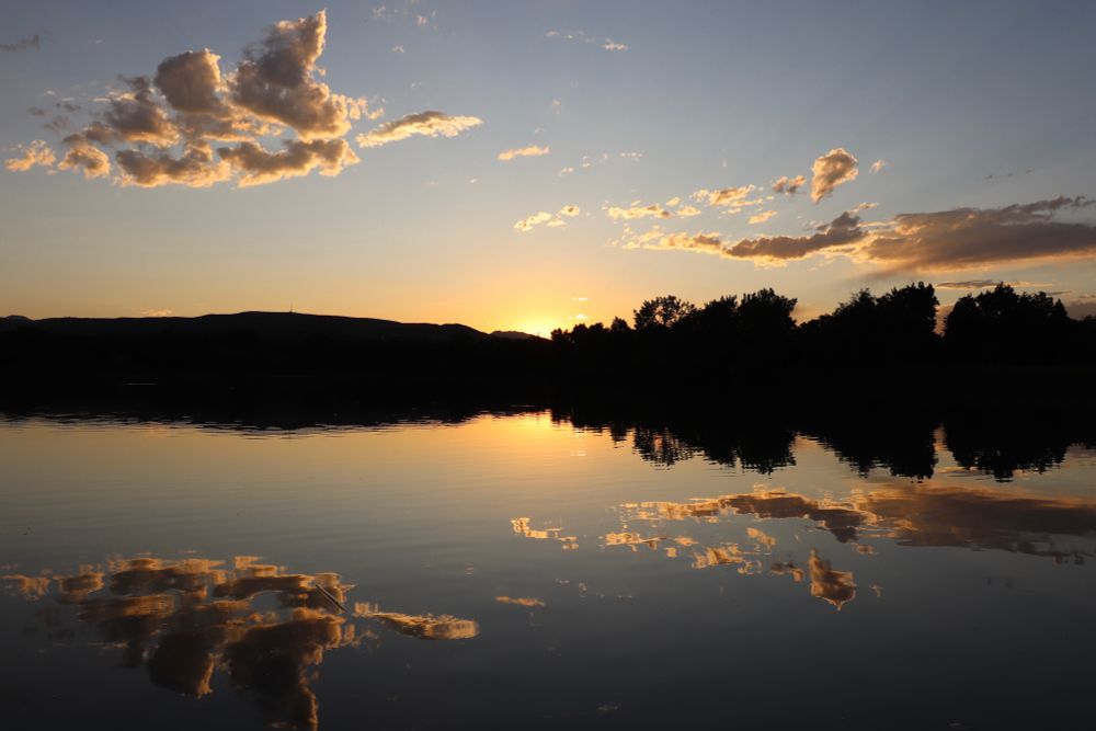 Sunset horizon reflection. Clouds mirrored in lake reflection