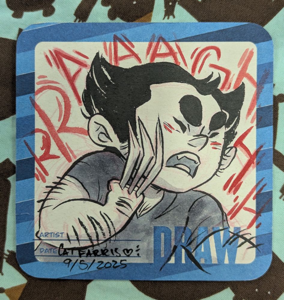 A coaster meant for sketching on decorated with the word Draw. It's got a black and white drawing of chibi wolverine not in costume looking mad. Behind it large red letters read "rraaaaghhh"