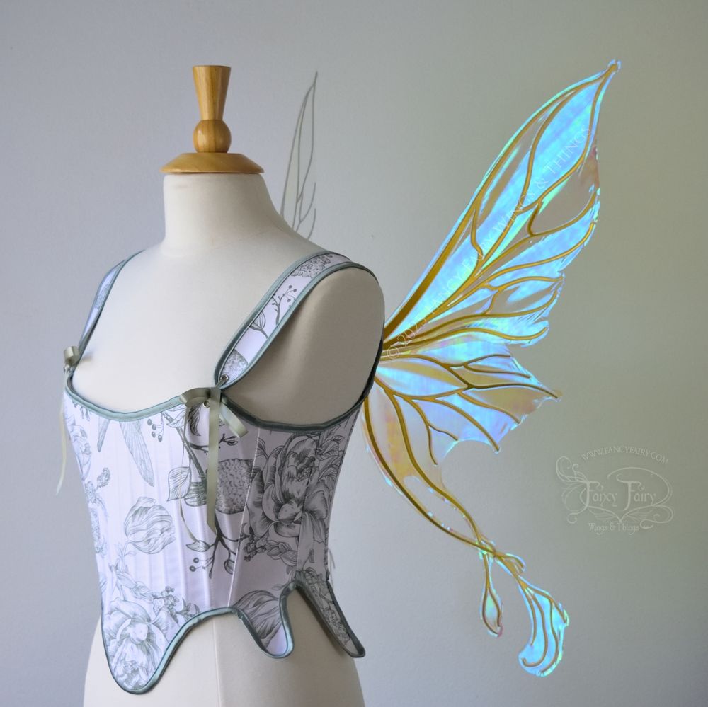 Transparent blue / green iridescent fairy wings with pointed upper tips and 2 swirling tails on the bottom panels with gold veins, worn on a dress form, right side view