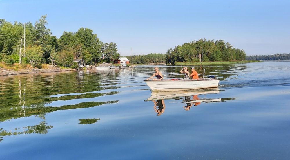 Schärenlandschaft, im Mittelpunkt ein Boot mit 3 Personen auf sanften Wellen