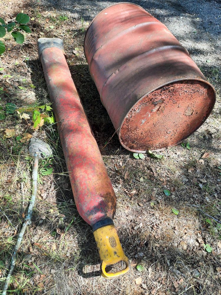 Eine verrostete Tonne und Gastube liegen auf der Erde.