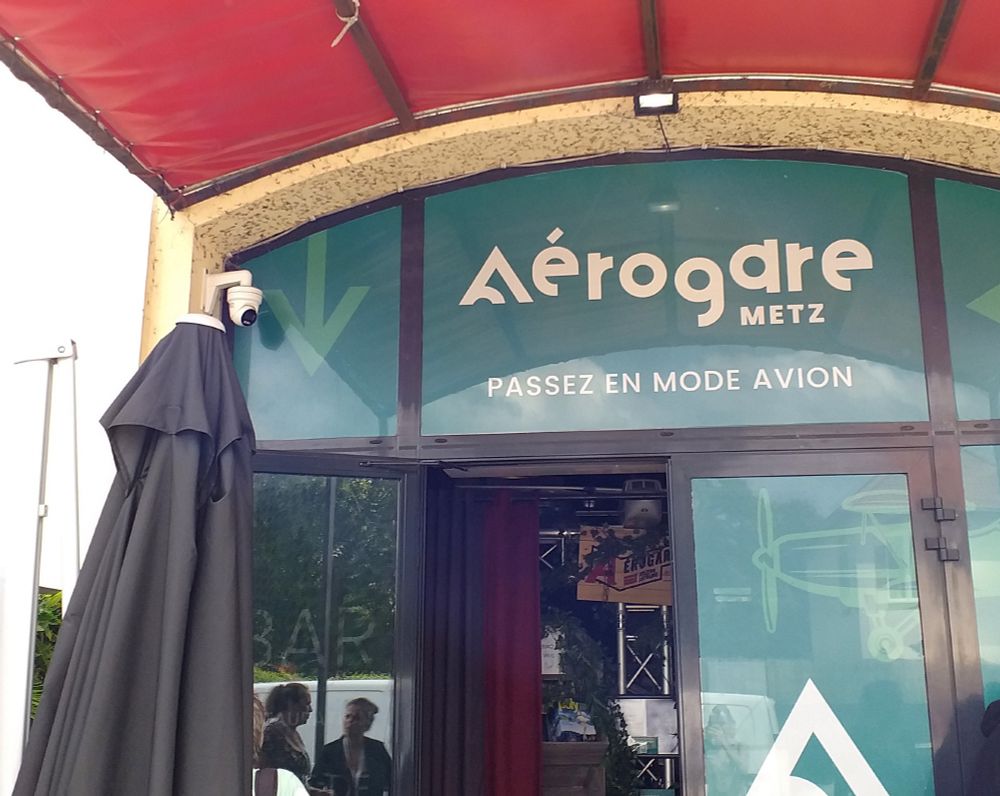 Porte d'entrée de l'Aérogare Metz avec la phrase d'accueil : "passez en mode avion".