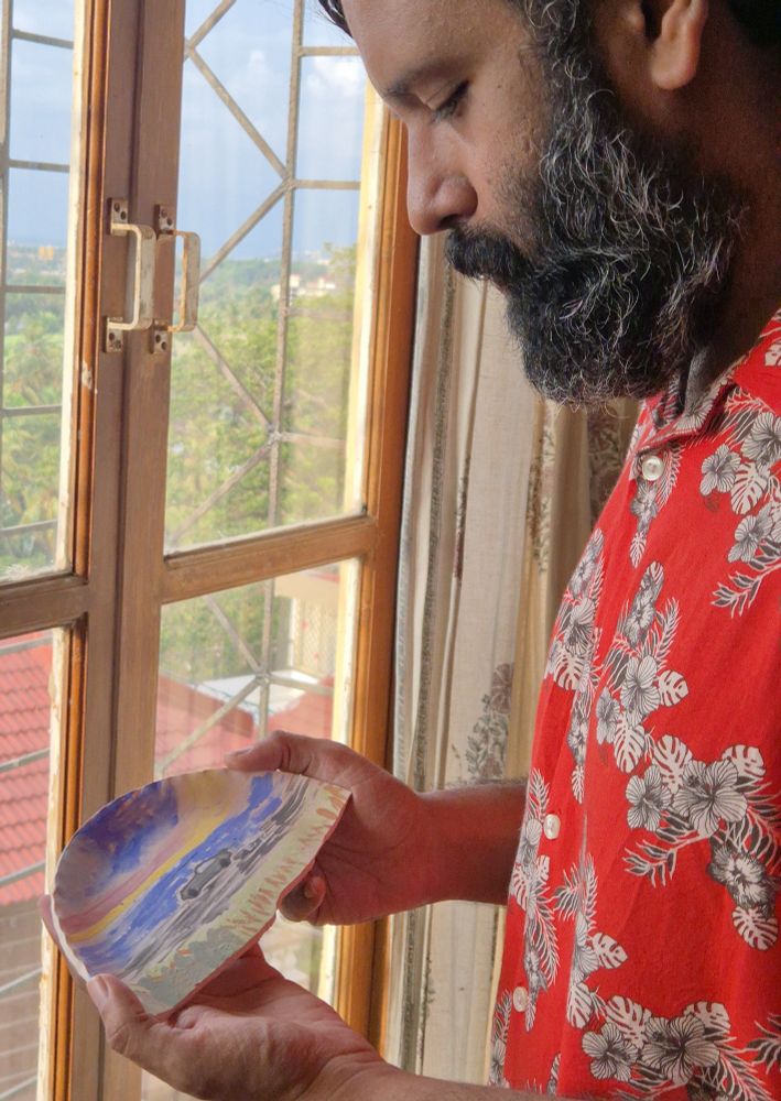 A man (idiot; myself) holding a half plate with a car sketched on it.