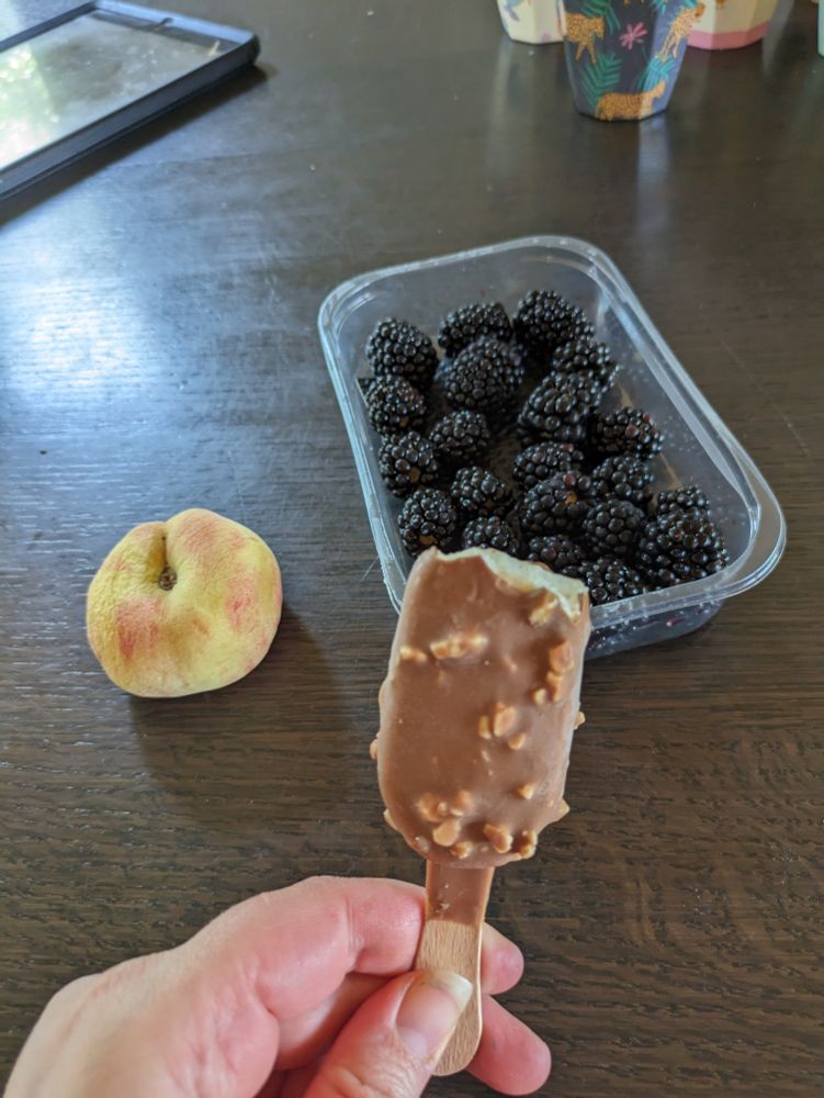 An offbrand mini magnum with milk chocolate and hazelnut, a peach, and blackberries