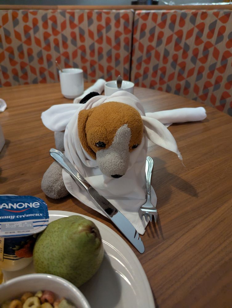 A stuffed dog with a napkin and cutlery at the table