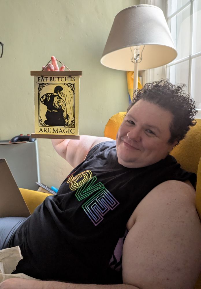 My beloved fat butch holding a "fat butches are magic" print