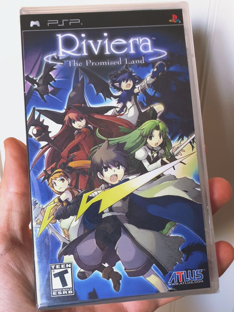Holding a copy of Riviera: the Promised Land for the PSP