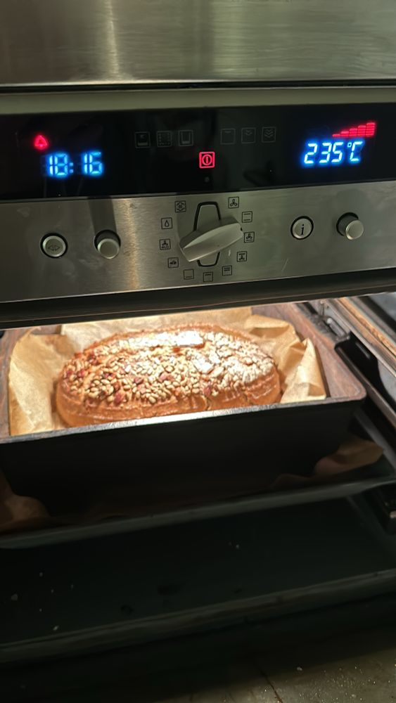 A nearly finished sourdough loaf in a Dutch oven, nestled in baking parchment and topped with seeds. The temperature reads 235 degrees (Celsius) and it’s 6:16pm